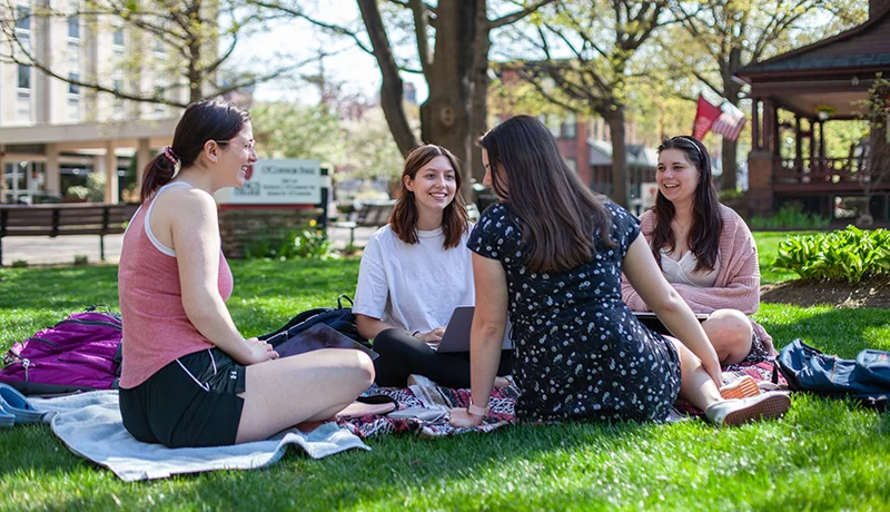 four students sitting outside
