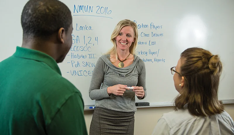 political science degree students and a professor talking in front of a whiteboard