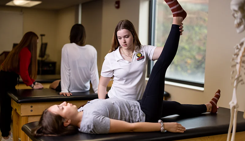 pre-med student lifting a patient's leg