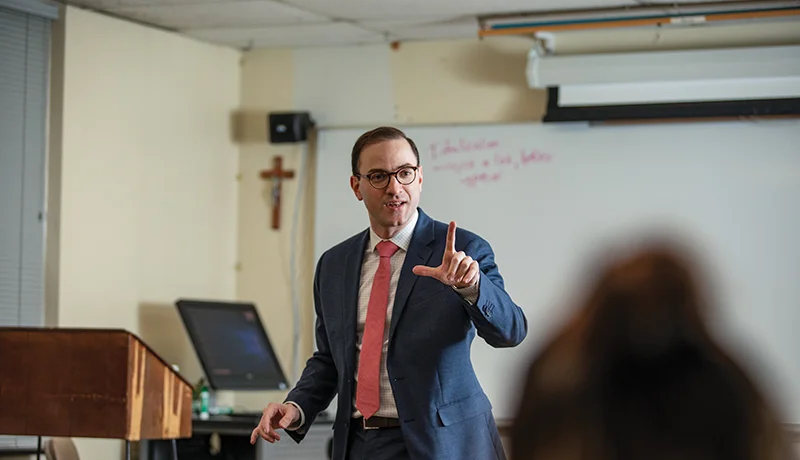 Theology degree professor speaking to students in classroom.