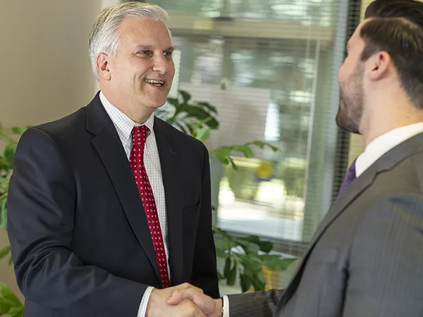 student earning bachelor's degree in human resources shaking hands with a professor