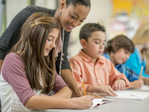 a teacher helping children with classwork in school, part of middle school education