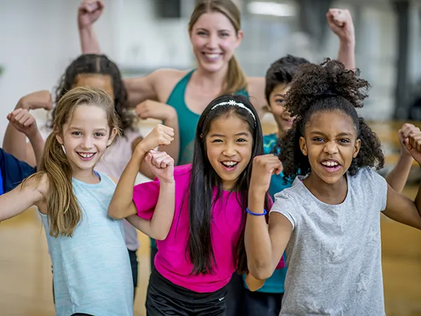 students flexing their biceps in the gymnasium, part of physical education teaching