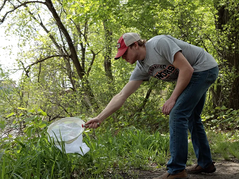 student outdoors collecting refuse