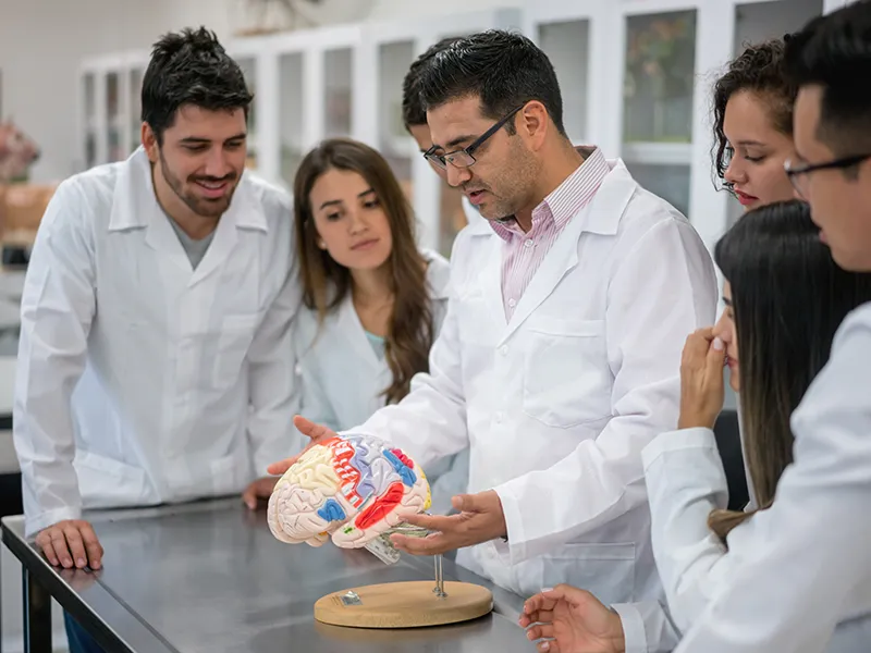 students in labcoats looking at a funnel