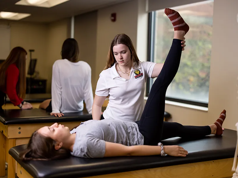 a student stretching a patient's leg